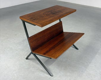 May include: A mid-century modern side table with a dark wood top and shelf. The table has a unique angled design with a dark metal frame. The wood has a rich, warm tone, and the table is set against a neutral background.