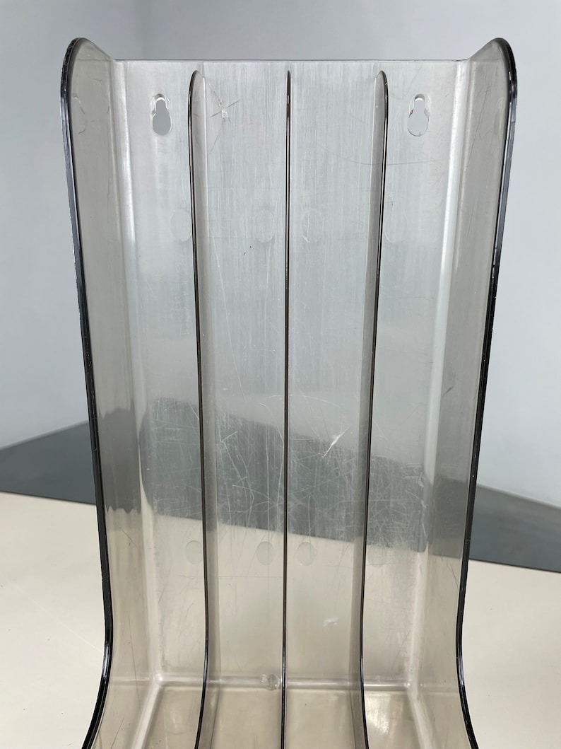 Pu&ograve; includere: Un porta riviste in plastica trasparente con quattro scomparti. Il porta riviste ha due fori nella parte superiore per appenderlo.