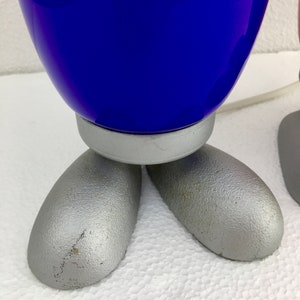 May include: A pair of blue and pink glass lamps with silver bases and feet. The lamps are shaped like a rounded rectangle and have a smooth, glossy finish.