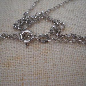 Pode incluir: Close-up de um fecho de colar de corrente de prata com fecho de mosquet&atilde;o. O fecho &eacute; marcado com o texto "925 Italy".