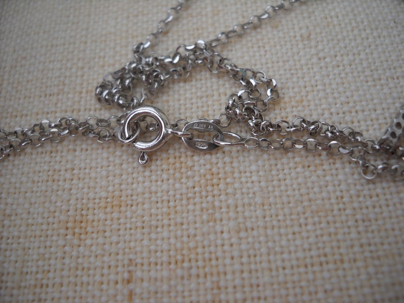 Pode incluir: Close-up de um fecho de colar de corrente de prata com fecho de mosquet&atilde;o. O fecho &eacute; marcado com o texto "925 Italy".