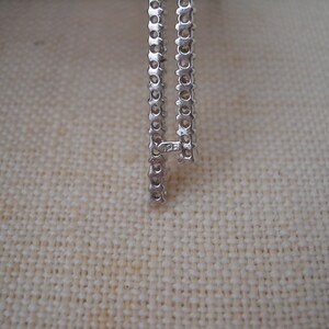 Pode incluir: Close-up de uma corrente de prata com um fecho que diz "125".