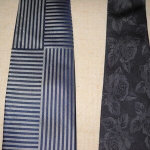 May include: Two neckties, one with a striped pattern in shades of blue and grey, and the other with a black floral pattern.