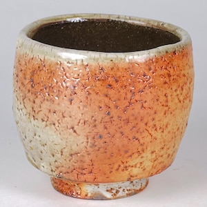 May include: A handcrafted ceramic bowl with a textured, mottled surface. The bowl features a gradient of colors, transitioning from a light beige at the base to a warm orange and brown at the top. The interior is a dark brown.