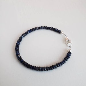 K&ouml;nnte beinhalten: Ein Armband aus dunkelblauen Saphiren mit einem silbernen Verschluss.