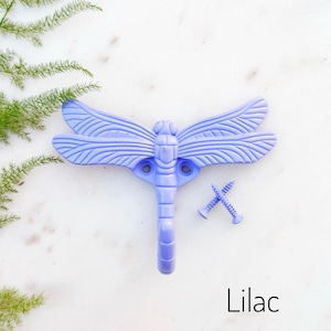 May include: Lilac dragonfly wall hook with two screws. The hook is shaped like a dragonfly with detailed wings and a body that forms a hook.