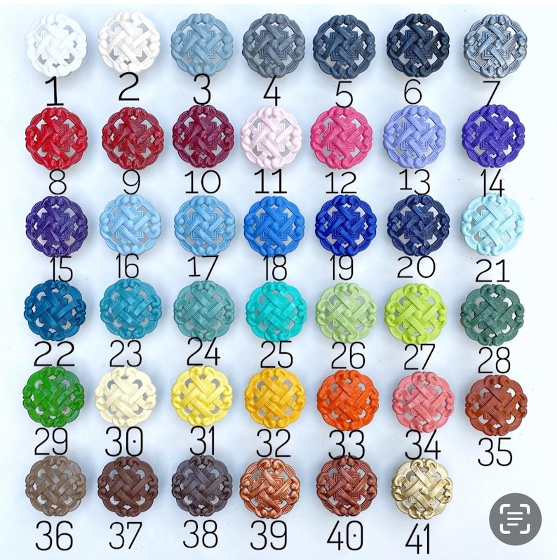 K&ouml;nnte beinhalten: Eine Sammlung von 41 dekorativen runden Kn&ouml;pfen in verschiedenen Farben, angeordnet in Reihen. Zu den Farben geh&ouml;ren Wei&szlig;, Grau, Rot, Rosa, Blau, Gr&uuml;n, Gelb, Orange und Braun. Jeder Knopf hat ein gewebtes Design und ist nummeriert.