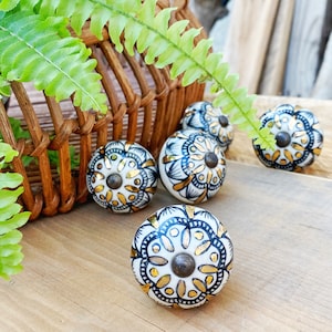 May include: Set of six white ceramic drawer knobs with black and gold mandala designs.