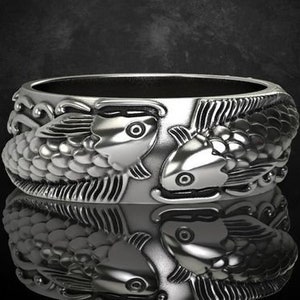 Op de afbeelding: Een zilveren ring met een gedetailleerd ontwerp van twee koi-karpers die tegenover elkaar staan. De vissen hebben schubben en vinnen, en de ring heeft een gepolijste afwerking. De ring wordt gepresenteerd op een reflecterend oppervlak.