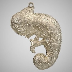 May include: A silver-colored chameleon pendant with intricate, detailed carvings. The pendant is a detailed, ornate design.