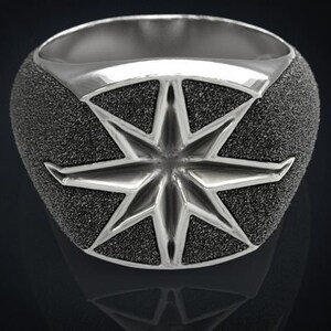 May include: A silver ring with a textured, star-shaped design. The ring is a statement piece with a bold, geometric design.