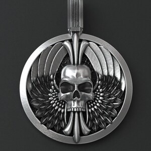 May include: A silver pendant featuring a detailed skull with wings and floral accents. The pendant is circular and has a bail for attaching to a chain.