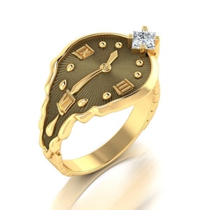 Könnte beinhalten: Goldfarbener Ring mit Zifferblatt-Design. Das Zifferblatt ist dunkelbraun mit goldenen römischen Ziffern und Zeigern. Oben ist ein quadratischer, klarer Edelstein eingesetzt. Der Ring hat ein einzigartiges, schmelzendes Aussehen.
