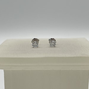 May include: A pair of silver stud earrings with a single round clear diamond in each earring.