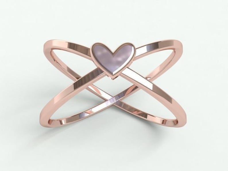K&ouml;nnte beinhalten: Ring aus Ros&eacute;gold mit einem Design aus &uuml;berlappenden B&auml;ndern. Der Ring hat ein herzf&ouml;rmiges Mittelst&uuml;ck mit einem hellvioletten Farbton. Das Design des Bandes erzeugt eine X-Form und verleiht dem Schmuck eine moderne Note.