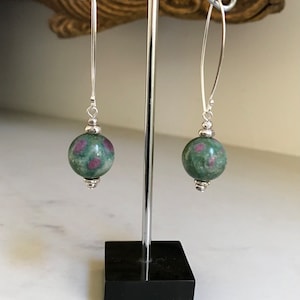 May include: A pair of silver dangle earrings with green and pink gemstone beads.
