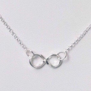 May include: A silver infinity necklace with a delicate chain. The infinity symbol is made of two interlocking circles.