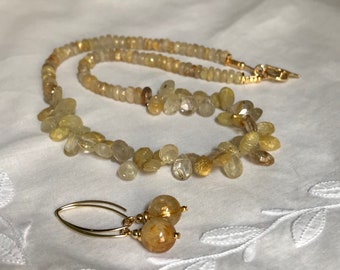 May include: A gold necklace and earrings set with a delicate chain and teardrop-shaped golden rutilated quartz beads.