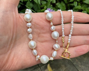 May include: Two pearl necklaces with gold clasps. One necklace features large, irregular pearls, while the other features smaller, round pearls.