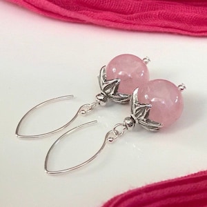 Puede incluir: Un par de pendientes de plata con cuentas de piedras preciosas rosas y detalles florales.