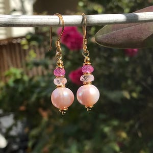 May include: A pair of gold earrings with pink pearls and pink and white gemstones.