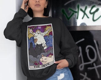 May include: Black sweatshirt with a graphic of a tarot card depicting the Devil. The card features three cats, one with wings and a halo, and the text "THE DEVIL" at the bottom.