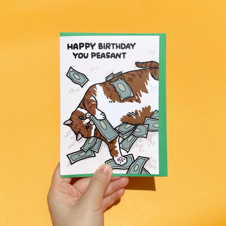 Puede incluir: Tarjeta de felicitaci&oacute;n con borde verde. Presenta un gato de dibujos animados marr&oacute;n y blanco rodeado de dinero, con el texto "HAPPY BIRTHDAY YOU PEASANT".