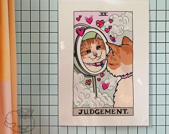 Può includere: Una carta dei tarocchi con un gatto che si guarda allo specchio. La carta è rosa e bianca con il numero XX e la parola "GIUDIZIO" stampata su di essa. Il gatto è arancione e bianco con un collare rosa. Ci sono cuori rosa e nuvole intorno al gatto.