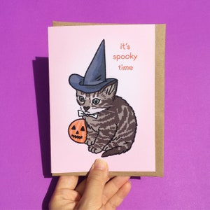 Es la hora espeluznante de Halloween Calabaza Linda bruja Gato Meme tarjeta - Tarjeta de gato lindo espeluznante, Tarjeta de meme de gato lindo y divertido, Tarjeta de felicitación de meme de Halloween
