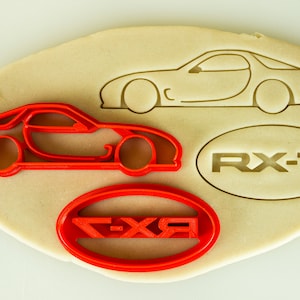 May include: Red plastic cookie cutters shaped like a car and two ovals with the words "RX-7" and "FXR" inside.