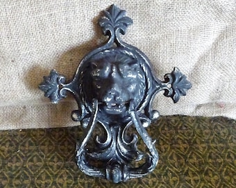 Può includere: Un batacchio per porta in ghisa nera con un design a testa di leone. Il batacchio presenta dettagli intricati e un anello decorativo.