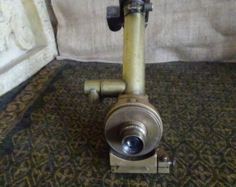 May include: A brass antique telescope with a lens and a focusing mechanism. The telescope is mounted on a base with a swiveling arm.