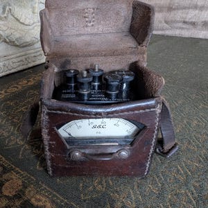Può includere: Una custodia in pelle marrone vintage con un misuratore di metallo all'interno. Il misuratore ha un quadrante con numeri da 0 a 50 e il testo "S&C" e "F.G.".