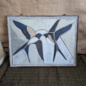 May include: Rectangular wall art with a bird design. The artwork features a light background with a bird design in shades of blue, black, and white. The frame is a light grey colour.
