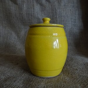 May include: A yellow ceramic jar with a lid. The jar has a crackled glaze and a rounded shape.