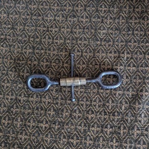 May include: A metal tool with two loops on either end and a threaded center section. The tool is silver in color and has a brass-colored center section.