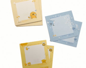 May include: A set of four yellow and blue memo pads with different illustrations. The pads feature a dog, a koala, a bee, and a jar of honey. The text on the pads reads "Sending you sunshine", "Sending you the biggest love", "Whipping up a honey-filled day", and "We have the best bee in you".