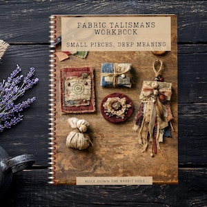 May include: A spiral-bound workbook titled Fabric Talismans Workbook: Small Pieces, Deep Meaning, featuring a wood-grain cover with images of handmade fabric charms, layered textile ornaments, and a small pouch, with Alice Down The Rabbit Hole text.