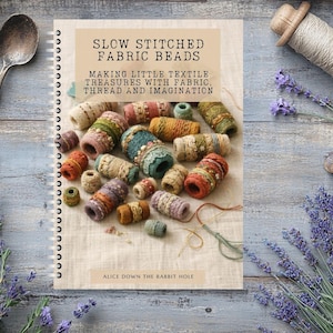 Può includere: Un libro con rilegatura a spirale intitolato Slow Stitched Fabric Beads: Making Little Textile Treasures with Fabric, Thread and Imagination di Alice Down the Rabbit Hole, che presenta una collezione di perline in tessuto colorate e testurizzate sulla copertina.