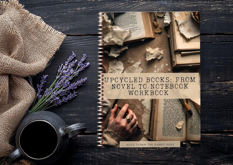May include: A spiral-bound workbook titled "Upcycled Books: From Novel to Notebook Workbook" with open books and torn paper. A sprig of lavender, a black mug, and a burlap cloth are arranged on a dark wooden surface.