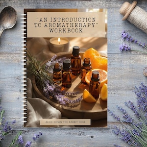 Könnte beinhalten: Aromatherapie-Arbeitsbuch mit dem Titel „Einführung in die Aromatherapie“ mit ätherischen Ölflaschen, Orangenscheiben und Lavendel auf einem Holztablett. Das Cover ist spiralgebunden. Das Bild enthält einen Löffel, Bindfaden und eine brennende Kerze.