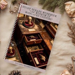 Puede incluir: Un cuaderno encuadernado en espiral titulado "Story Scraps Workbook: The Museum of Misplaced Oddities" con una ilustración de un mueble con cajones abiertos que muestran curiosidades. La portada está rodeada de flores secas y piñas.