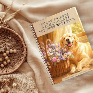 May include: A spiral-bound workbook titled "Furry Friends Aromatherapy for Dogs Workbook" featuring a golden retriever dog with a basket of flowers. The book is on a beige surface with a woven basket and decorative elements.