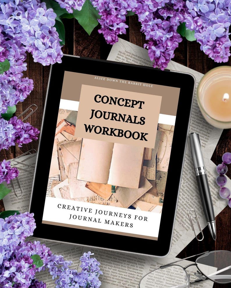 Może przedstawiać: Tablet wyświetla okładkę zeszytu ćwiczeń zatytułowanego "Concept Journals Workbook" ze sloganem "Creative Journeys for Journal Makers". Obraz otoczony jest fioletowymi kwiatami, długopisem, okularami i zapaloną świecą, tworząc kreatywną atmosferę.