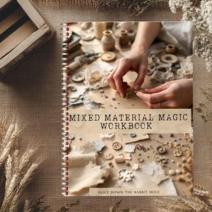 May include: A spiral-bound workbook titled "Mixed Material Magic Workbook" with a collage of craft supplies. The image shows hands arranging small objects, buttons, and fabric scraps. The background includes a wooden crate and wheat stalks.