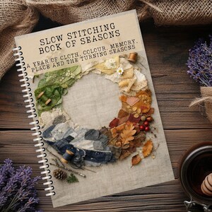 Może przedstawiać: Spiralnie oprawiona książka zatytułowana SLOW STITCHING BOOK OF SEASONS A YEAR OF CLOTH, COLOUR, MEMORY, PLACE AND THE TURNING SEASONS. Okładka przedstawia okrągły kolaż ze skrawków materiału w kolorach zielonym, żółtym, pomarańczowym i niebieskim, ozdobiony małymi drewnianymi szpulkami, szyszką i czerwonymi jagodami.