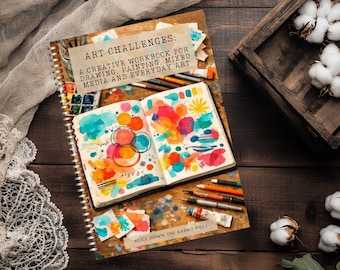 Könnte beinhalten: Ein spiralgebundenes Arbeitsbuch mit dem Titel ART CHALLENGES: A CREATIVE WORKBOOK FOR DRAWING, PAINTING, MIXED MEDIA AND EVERYDAY ART. Das Cover zeigt ein offenes Skizzenbuch mit bunten Aquarellkreisen, abstrakten Formen und Kunstbedarf.