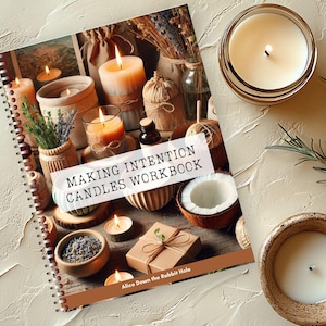 Könnte beinhalten: Ein Spiralbuch mit dem Titel "Making Intention Candles Workbook" mit einem Titelbild, das brennende Kerzen, ätherische Öle und dekorative Elemente zeigt. Die Szene umfasst eine Kokosnuss, kleine Geschenke und einen Rosmarinzweig.