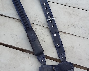 May include: A black leather holster with a shoulder strap and a blue stitching detail. The holster has a magazine pouch and a belt loop.
