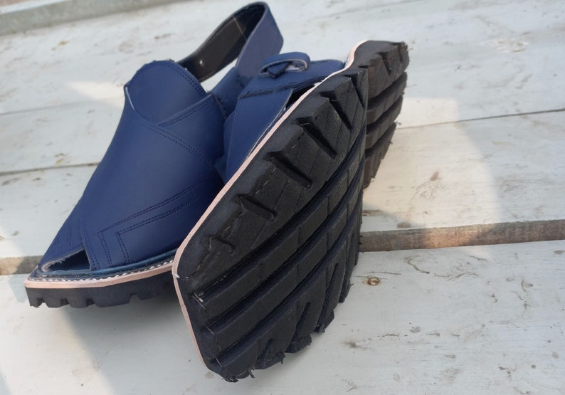 May include: A pair of blue leather sandals with a black rubber sole. The sandals have a strap that goes around the ankle and a toe loop.